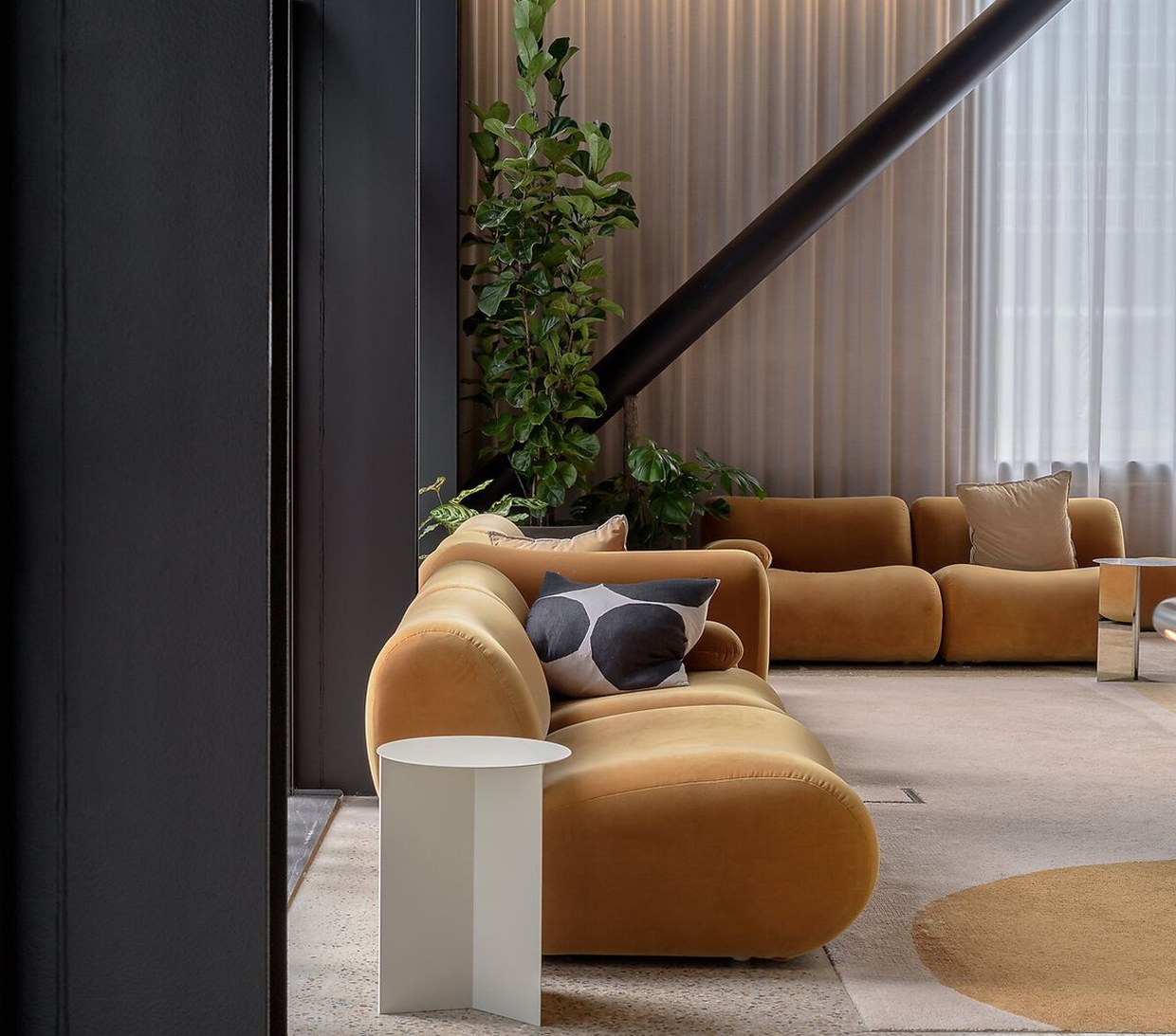 Loungehoek met een oranje bank en beplanting bij een raampartij